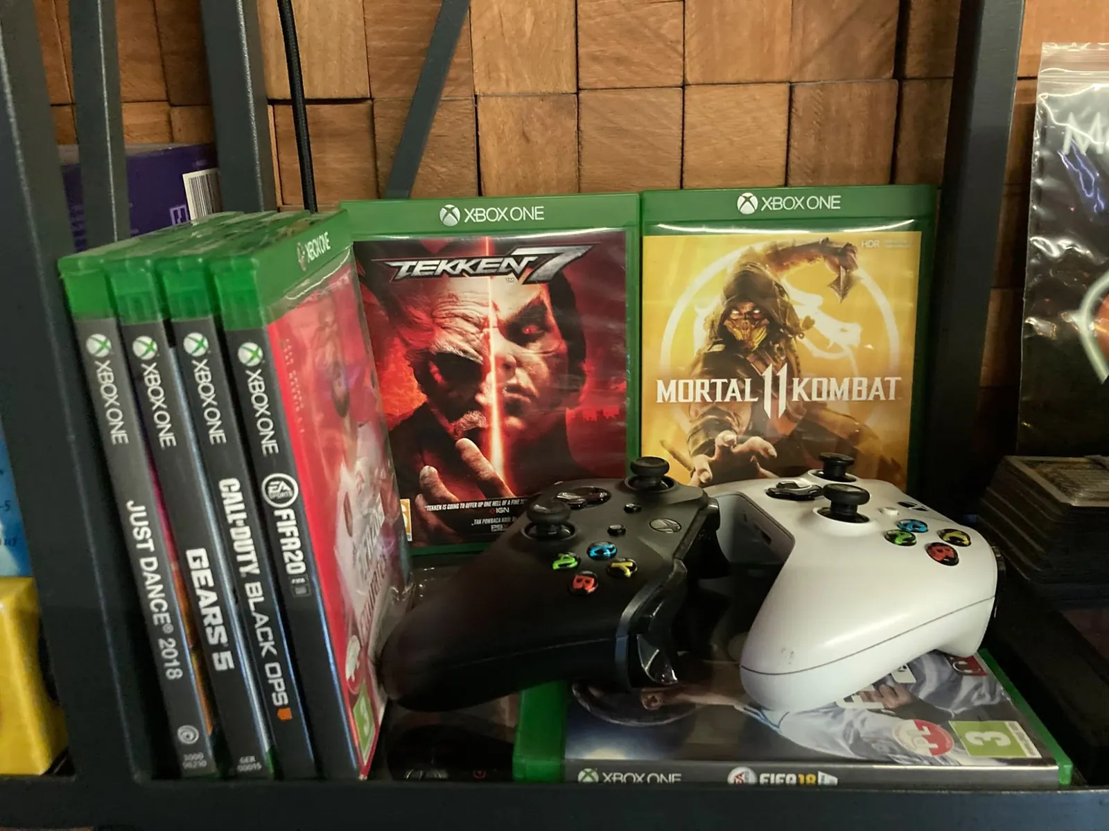 Gry na Xboxa i dwa pady na półce w Klubie Pictures