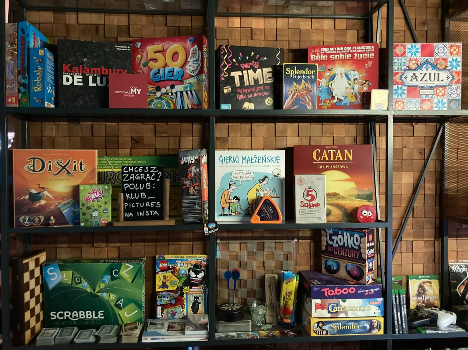 Półka z planszówkami w Klubie Pictures: Catan, Dixit, Azul, Scrabble i inne