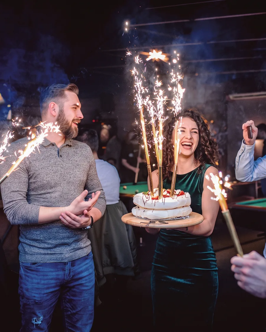 Goście z tortem z zimnymi ogniami na imprezie w Klubie Pictures